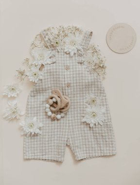 Çiçekli yumuşak bebek pantolonu. Moda yeni doğmuş, bohem tarzı, doğal bej renkler. Düz yerde, üst tarafta. Doğal tekstil, pastel arkaplan. 