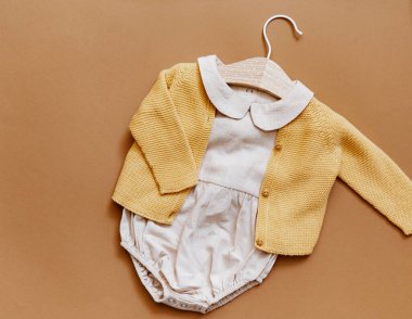 fashion newborn concept, baby clothes on brown background. Top view  clipart