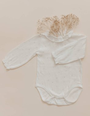 Doğal malzeme konsepti. Bej arka planda yumuşak bir bebek tulumu. Bohem bebek. 