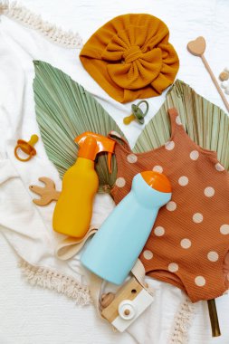 Bebek mayoları, plaj aksesuarları ve güneş kremi. Plastik güneş koruması şişesi. Çocuklar için krema. 