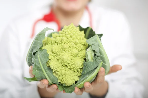 Young nutritionist showing roman cabbage — Stock Photo, Image