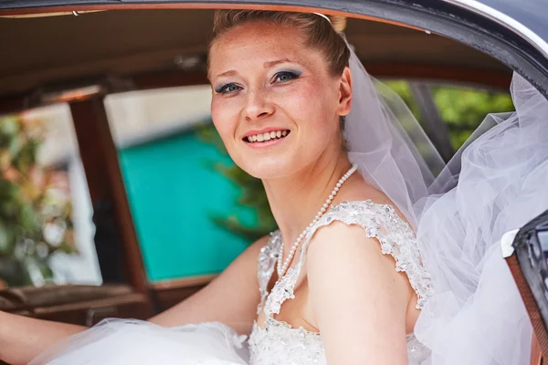 Beautiful blond bride posing inside car — Stock Photo, Image