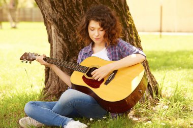 açık havada gitar ile gülümseyerek mutlu bir genç kadının portresi