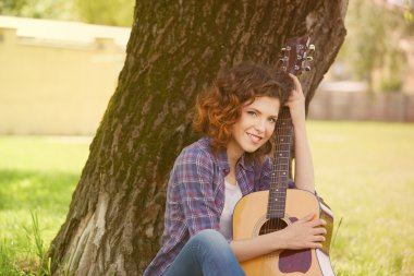 açık havada gitar ile gülümseyerek mutlu bir genç kadının portresi