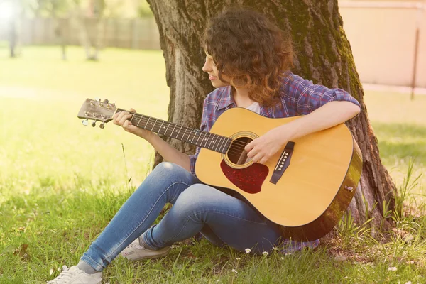 Porträt einer glücklichen jungen Frau mit Gitarre im Freien — Stockfoto