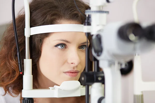Όμορφη γυναίκα ψάχνει σε μάτι μηχανή δοκιμής με συγκέντρωση στο εργαστήριο ΟΦΘΑΛΜΙΑΤΡΟΣ — Φωτογραφία Αρχείου