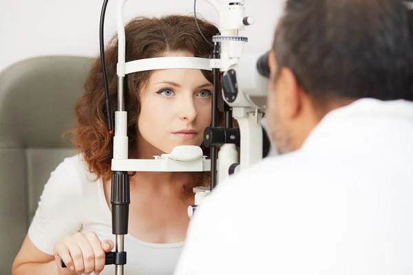 Krásná žena se dívá do očí zkušební stroj s koncentrací v laboratoři očnímu — Stock fotografie