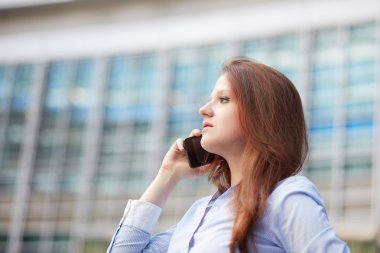 Genç iş kadını cep telefonuyla konuşuyor.