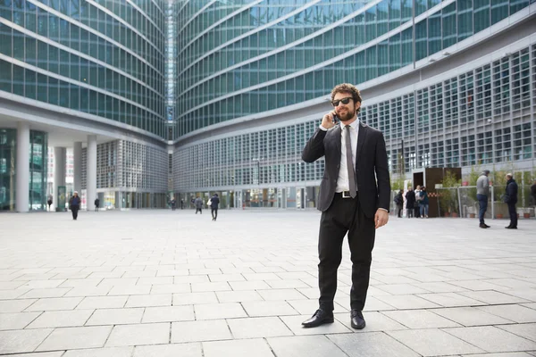 Hombre de negocios hablando con móvil fuera del edificio de oficinas — Foto de Stock