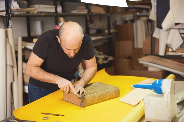 book binder restores old book in craft workshop