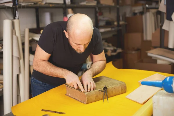 book binder restores old book in craft workshop