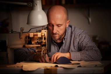 Korona virüsünün yayılmasını önlemek ve önlemek için dikiş makinesiyle çalışan adam ev yapımı yüz maskesi yapıyor.