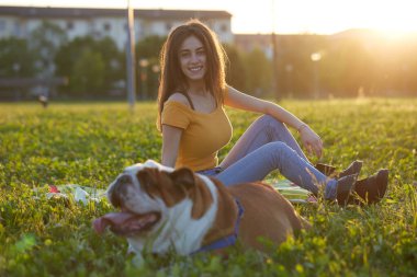 Genç esmer kız İngiliz bulldoguyla oynuyor.