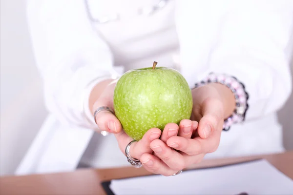 Young nutritionist showing apple in her office — Stock Photo, Image