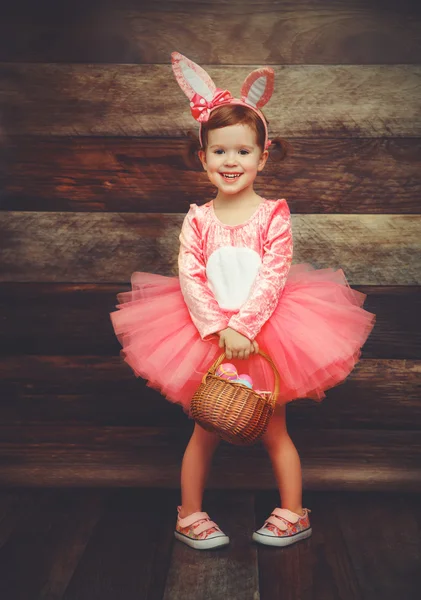Menina feliz em traje coelho da Páscoa coelho com ovos cesta — Fotografia de Stock
