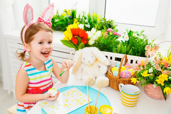 Happy child girl paints eggs for Easter — Stock Photo, Image