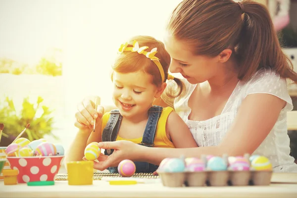 Šťastná rodina matka a dítě dívka maluje vajíčka na Velikonoce — Stock fotografie