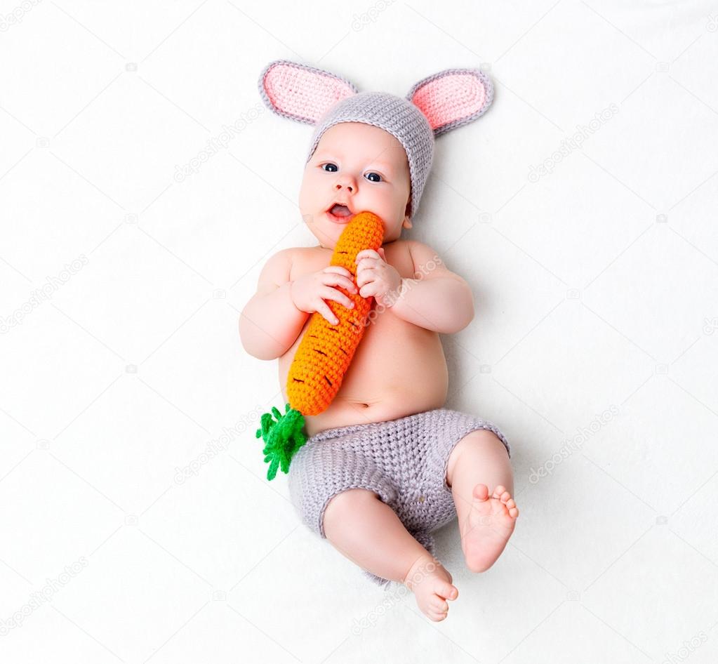 happy baby child in costume a rabbit bunny with carrot on a whit