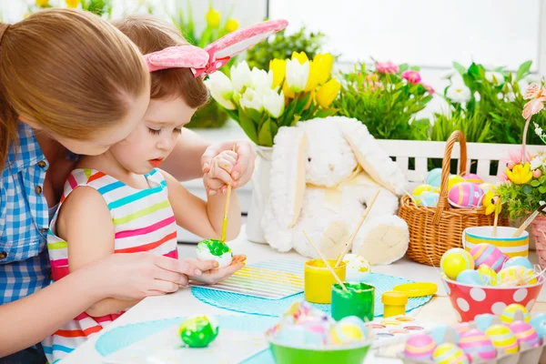 Feliz familia madre e hijo niña pinta huevos para Pascua — Foto de Stock