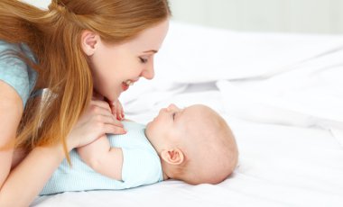 mutlu aile anne bebek yatakta ile oynarken