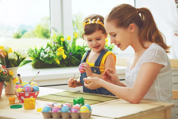 Šťastná rodina matka a dítě dívka maluje vajíčka na Velikonoce — Stock fotografie