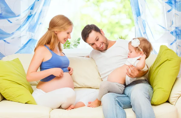 Счастливая семья. беременная мать, отец и дочь в доме — стоковое фото