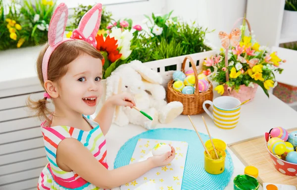 Šťastné dítě dívka maluje vajíčka na Velikonoce — Stock fotografie