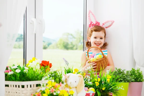 Påsk. lyckligt barn flicka med bunny öron och färgglada ägg sitti — Stockfoto