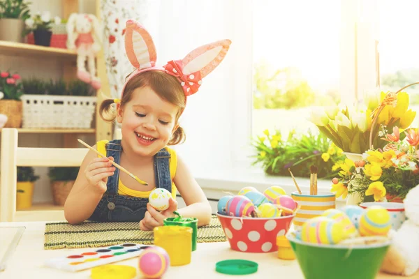 Šťastné dítě dívka maluje vajíčka na Velikonoce — Stock fotografie