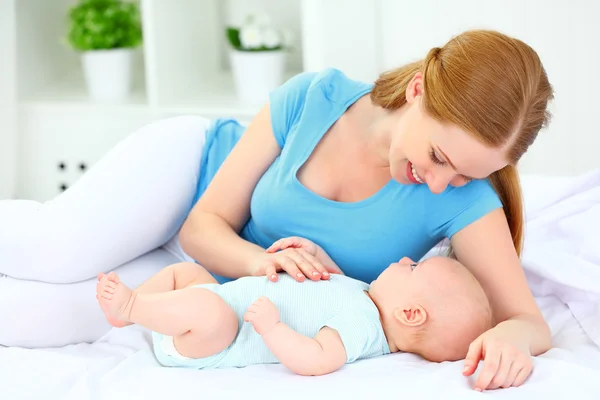 Felice madre di famiglia che gioca con il bambino a letto — Foto Stock