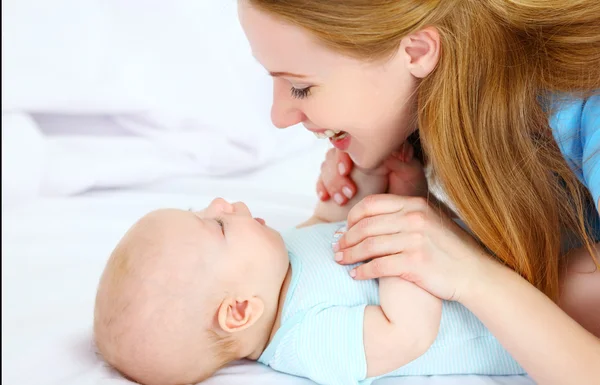 Gelukkige familie moeder spelen met baby in bed — Stockfoto