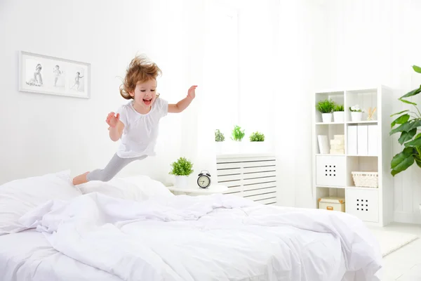 Niña feliz salta y juega a la cama — Foto de Stock