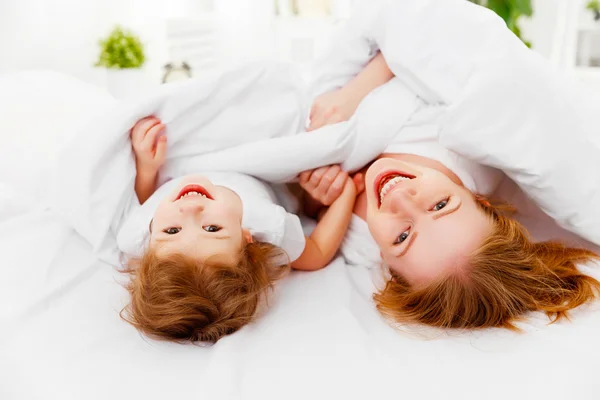 Feliz familia madre e hijo jugando y riendo en la cama — Foto de Stock