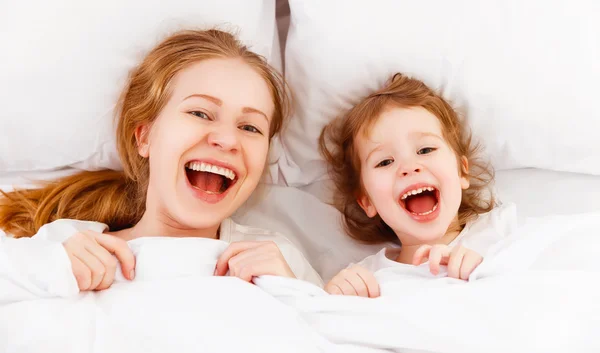 Feliz familia madre e hijo jugando y riendo en la cama —  Fotos de Stock