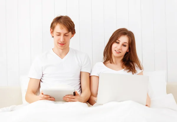 Feliz pareja con ordenador portátil en Internet en la cama — Foto de Stock