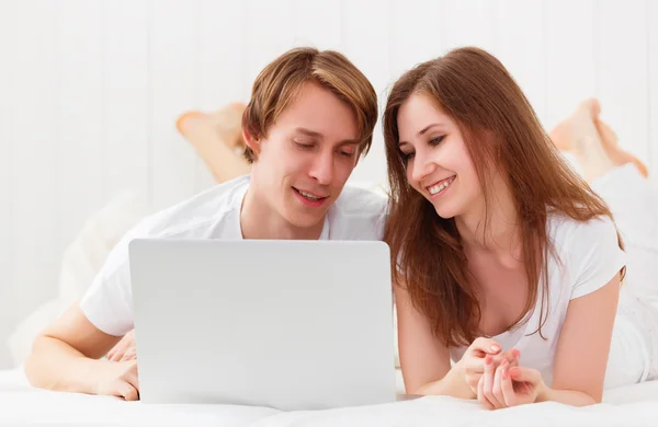 Счастливая пара с ноутбуком в Интернете в постели — стоковое фото