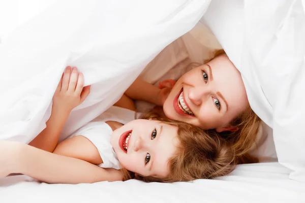 Feliz familia madre e hijo jugando y riendo en la cama —  Fotos de Stock