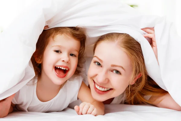 Família feliz mãe e criança brincando e rindo na cama — Fotografia de Stock