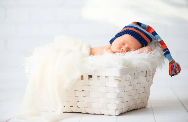 Bebê recém-nascido bonito em azul tricô cap dormindo em cesta — Fotografia de Stock