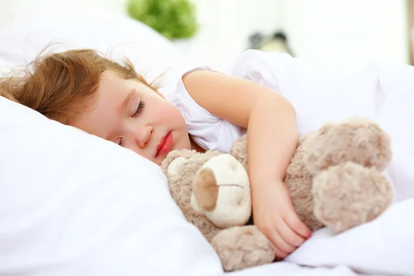 Çocuk oyuncak ayı ile yatakta uyur küçük kız — Stok fotoğraf