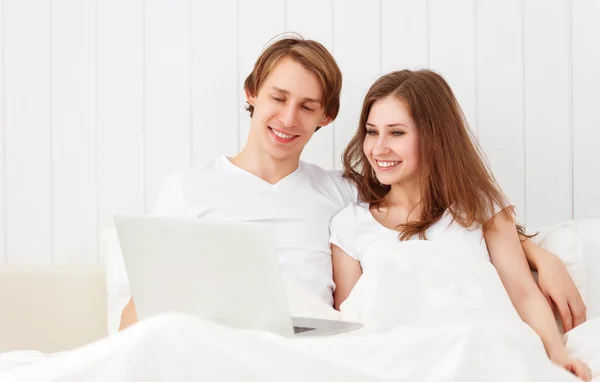 Happy couple with laptop on internet in bed — Stock Photo, Image