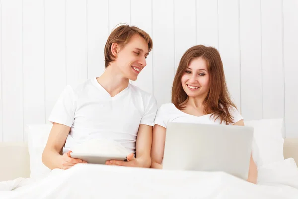 Happy couple with laptop on internet in bed — Stock Photo, Image