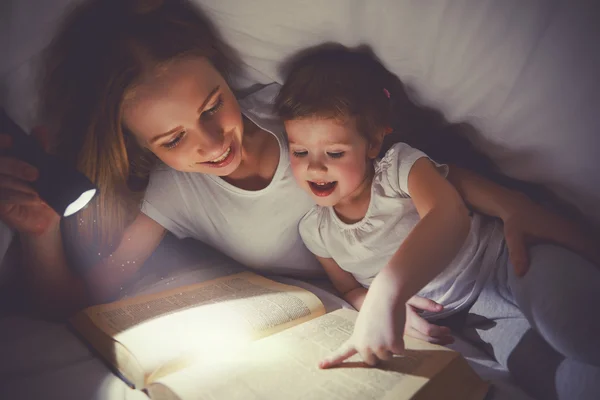 Rodzinne czytanie przed snem. Mama i dziecko czytanie książki z latarek — Zdjęcie stockowe