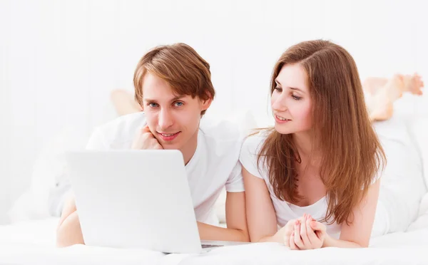 Feliz pareja con ordenador portátil en Internet en la cama — Foto de Stock