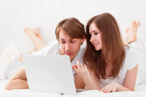 Happy couple with laptop on internet in bed — Stock Photo, Image