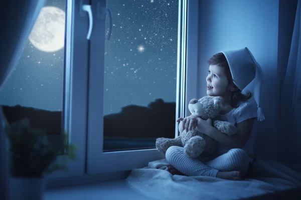 Enfant petite fille à fenêtre rêvant et admirant le ciel étoilé — Photo