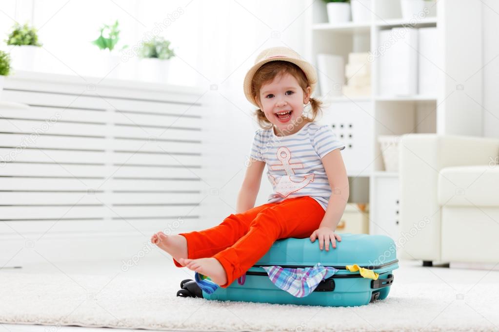 happy child girl packs clothes into suitcase for travel, vacatio