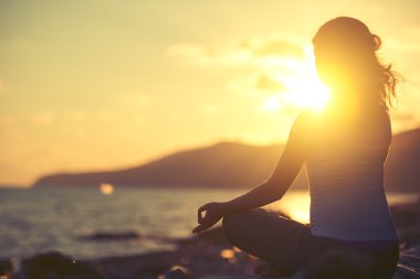 gün batımında sahilde lotus poz meditasyon kadın