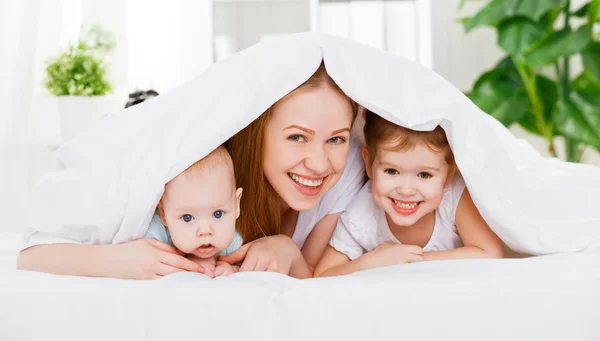 Feliz familia madre y dos hijos, hijo e hija en la cama un —  Fotos de Stock