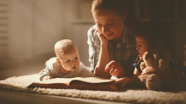 Gelukkige familie moeder en kinderen Lees een boek in de avond — Stockfoto